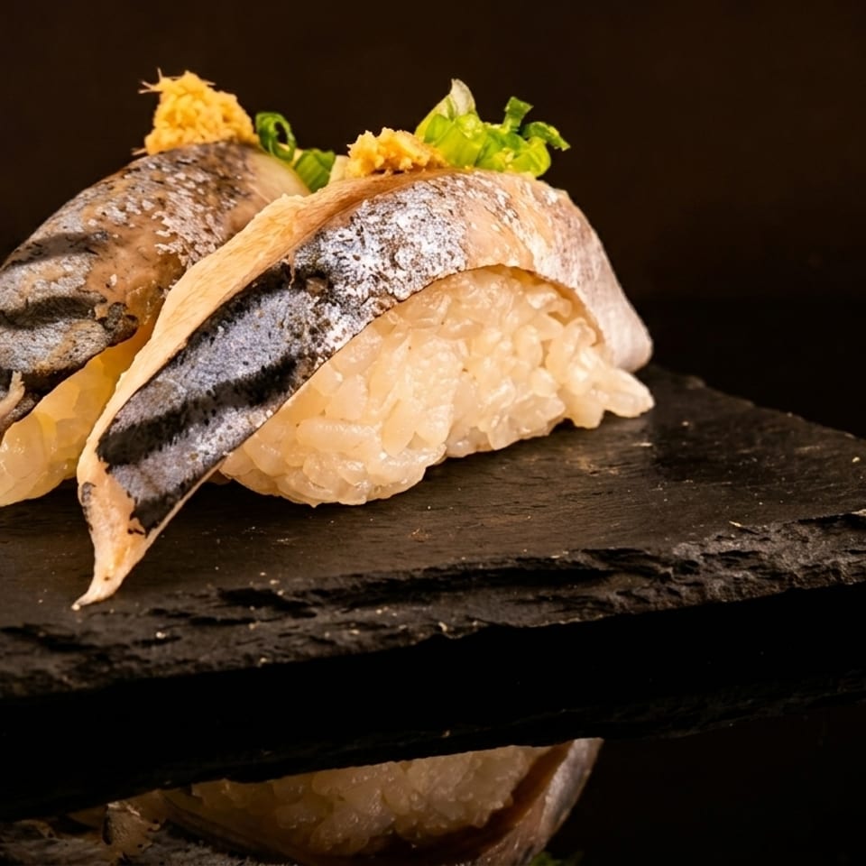 Two pieces of nigiri sushi with fish, rice, and green garnish on a dark slate plate.